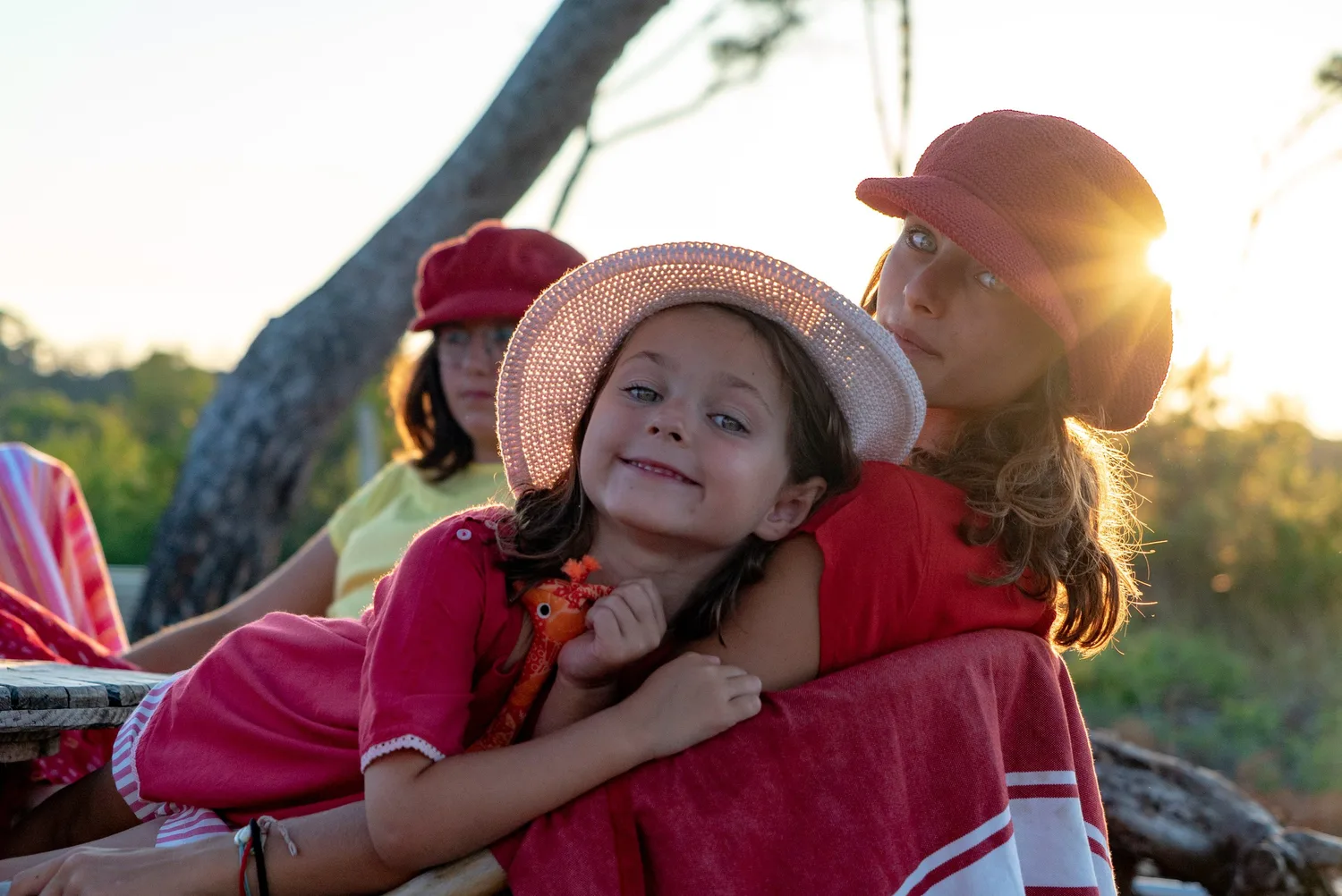 Trois jeunes filles au contre-jour dans le maquis de Porquerolles, chapeau de paille et casquettes rouges.