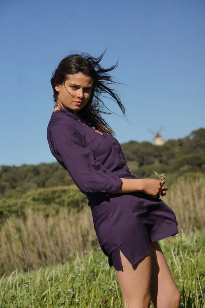 Femme en tunique prune dans les herbes hautes, moulin à vent sur la colline sous ciel bleu à Porquerolles.