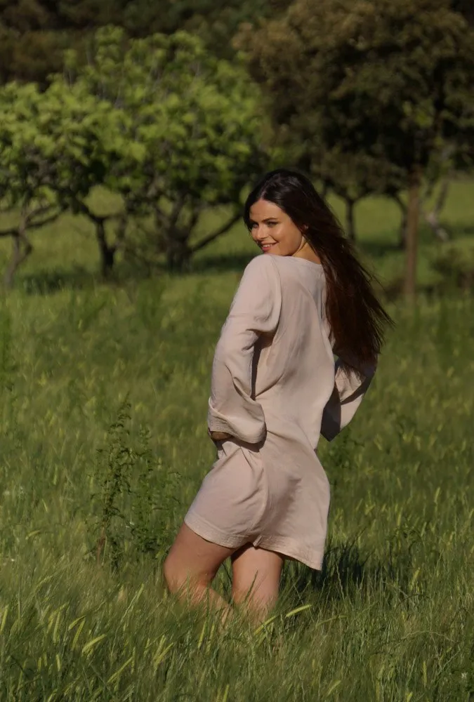 Femme en tunique claire, sourire par-dessus l'épaule, dans les herbes hautes du maquis à Porquerolles.