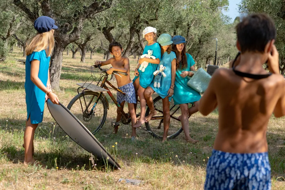 Enfants en tenues turquoise autour d'un vélo dans une oliveraie, séance photo à Porquerolles.