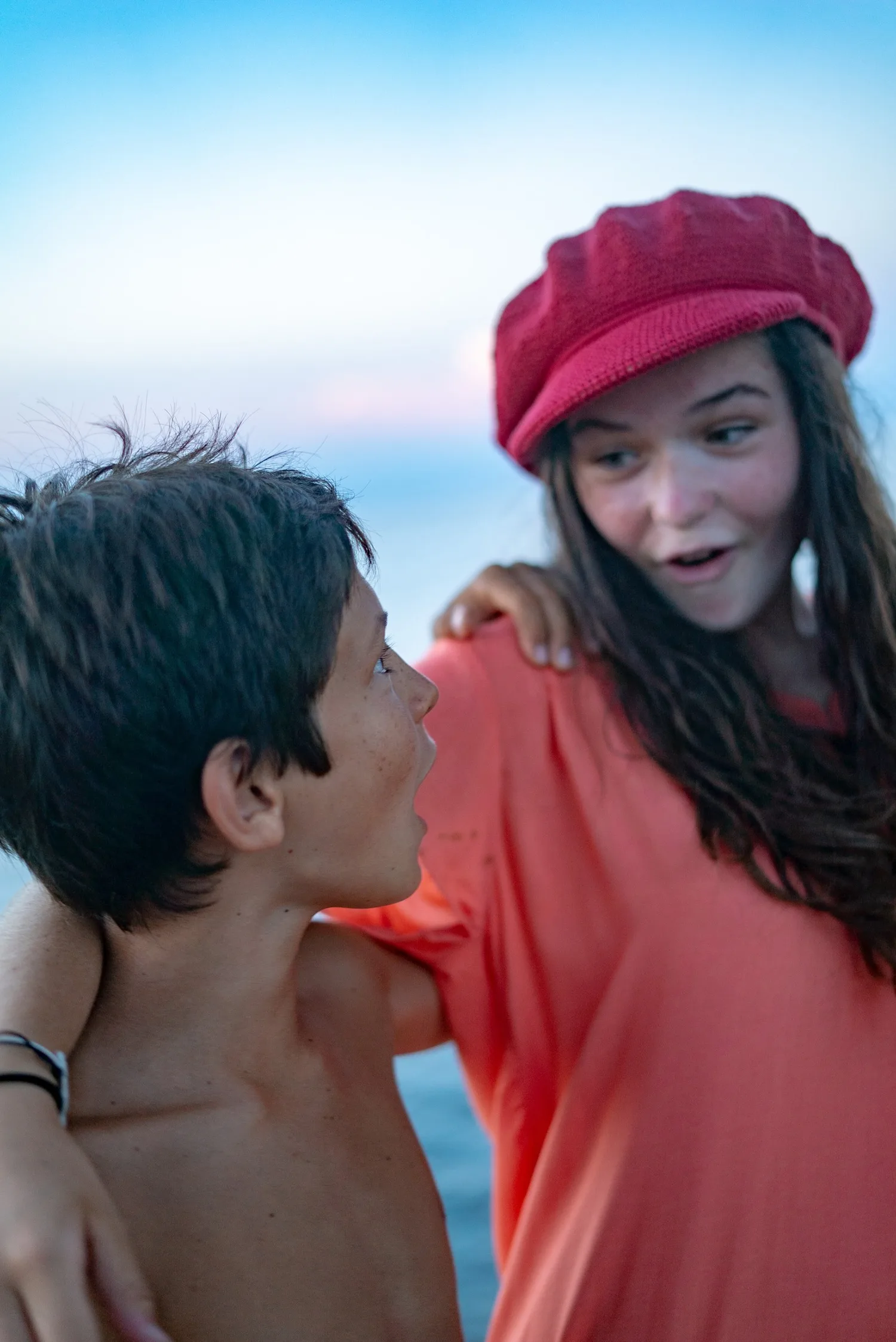Garçon et fillette en chapeau crochet rouge surpris sur un bateau, lumière douce de fin de journée à Porquerolles.