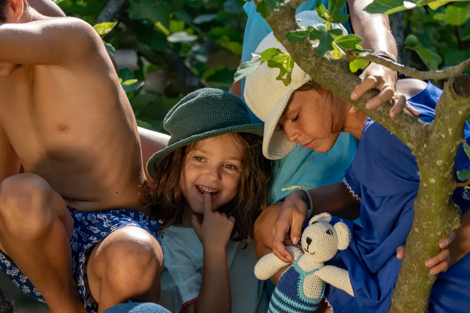 Enfants aux chapeaux crochet dans un figuier, robe bleue et ours crocheté à la main à Porquerolles.