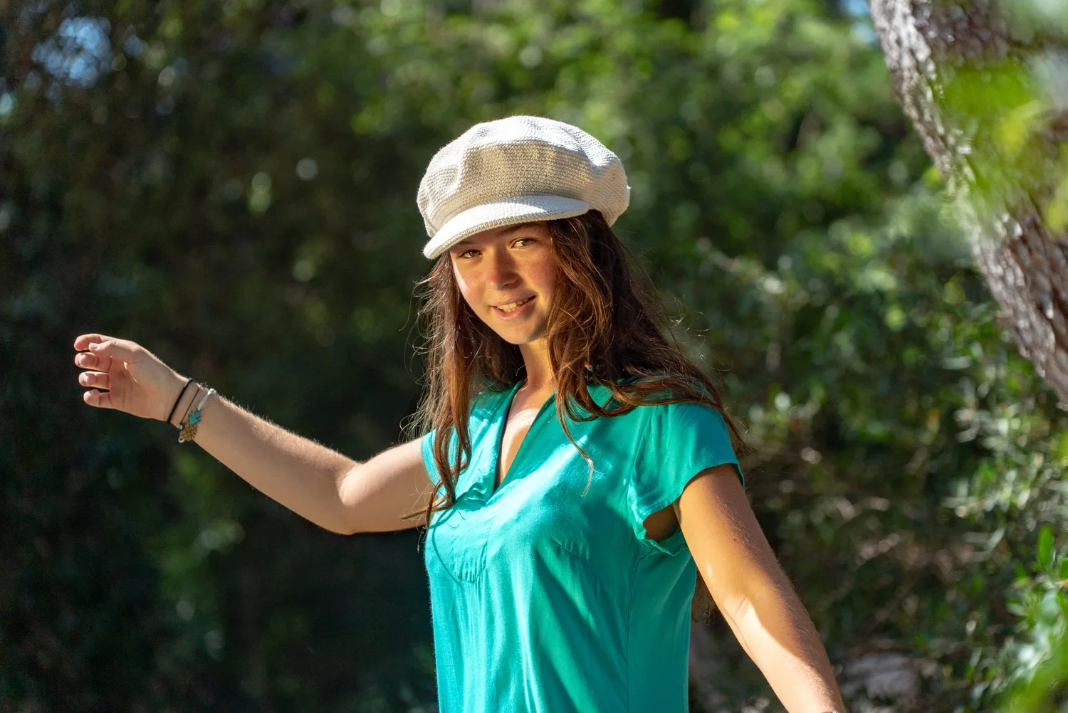 Adolescente souriante en tunique turquoise et casquette blanche au crochet dans le maquis à Porquerolles.