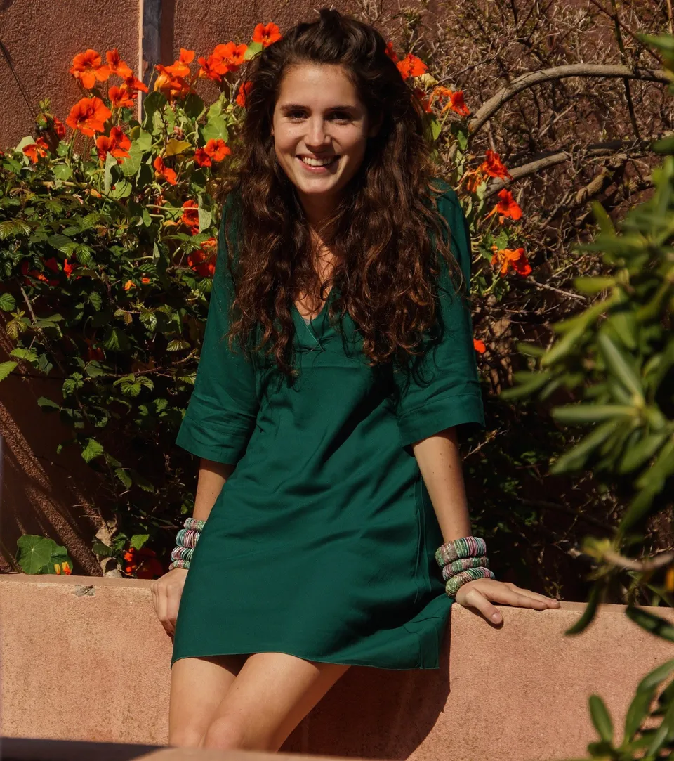 Femme en tunique grise et pantalon clair dans un jardin à Porquerolles.
