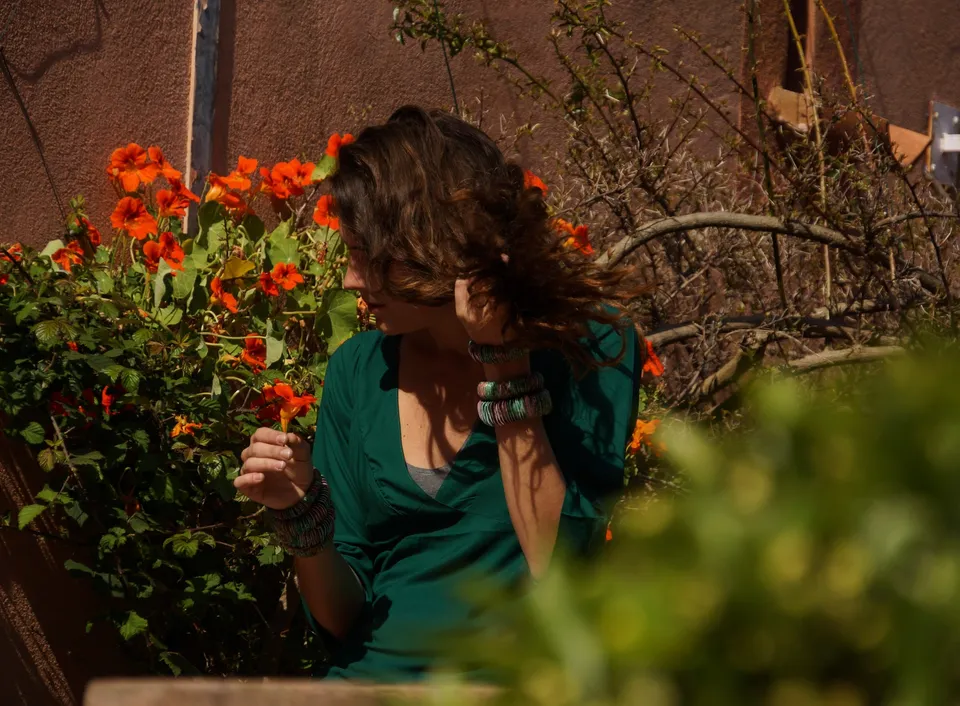 Femme en tunique grise et pantalon clair dans un jardin à Porquerolles.