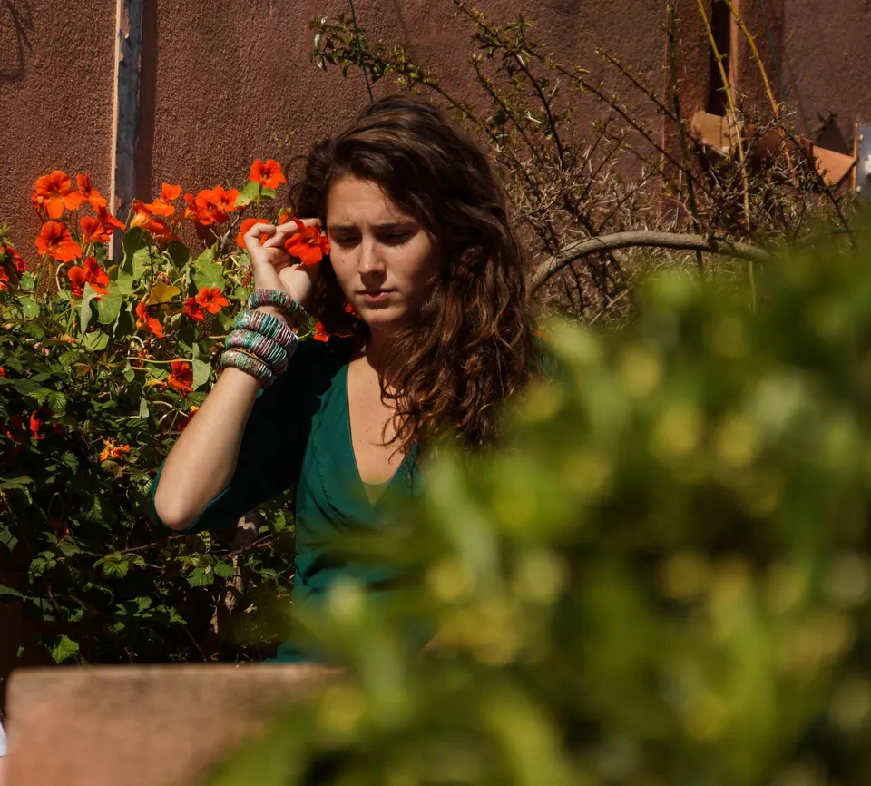 Femme en tunique grise et pantalon clair dans un jardin à Porquerolles.