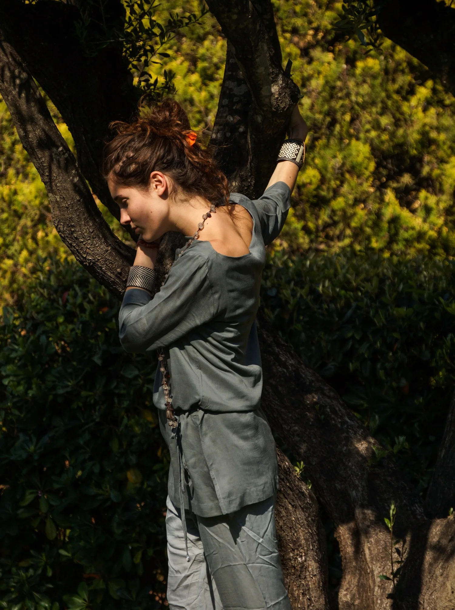 Femme en tunique grise et pantalon clair parmi les jardins de Porquerolles.