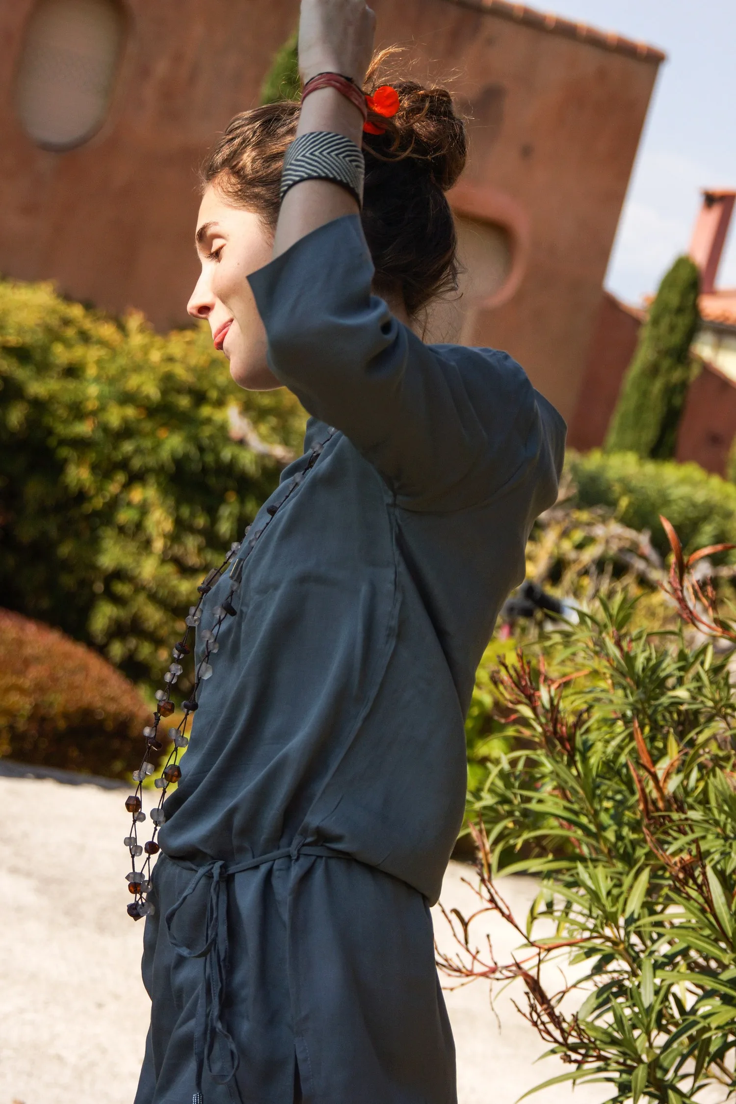 Femme en tunique grise et pantalon clair parmi les jardins de Porquerolles.