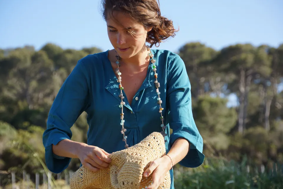 Femme en tunique bleue et chapeau de paille dans le maquis de Porquerolles.