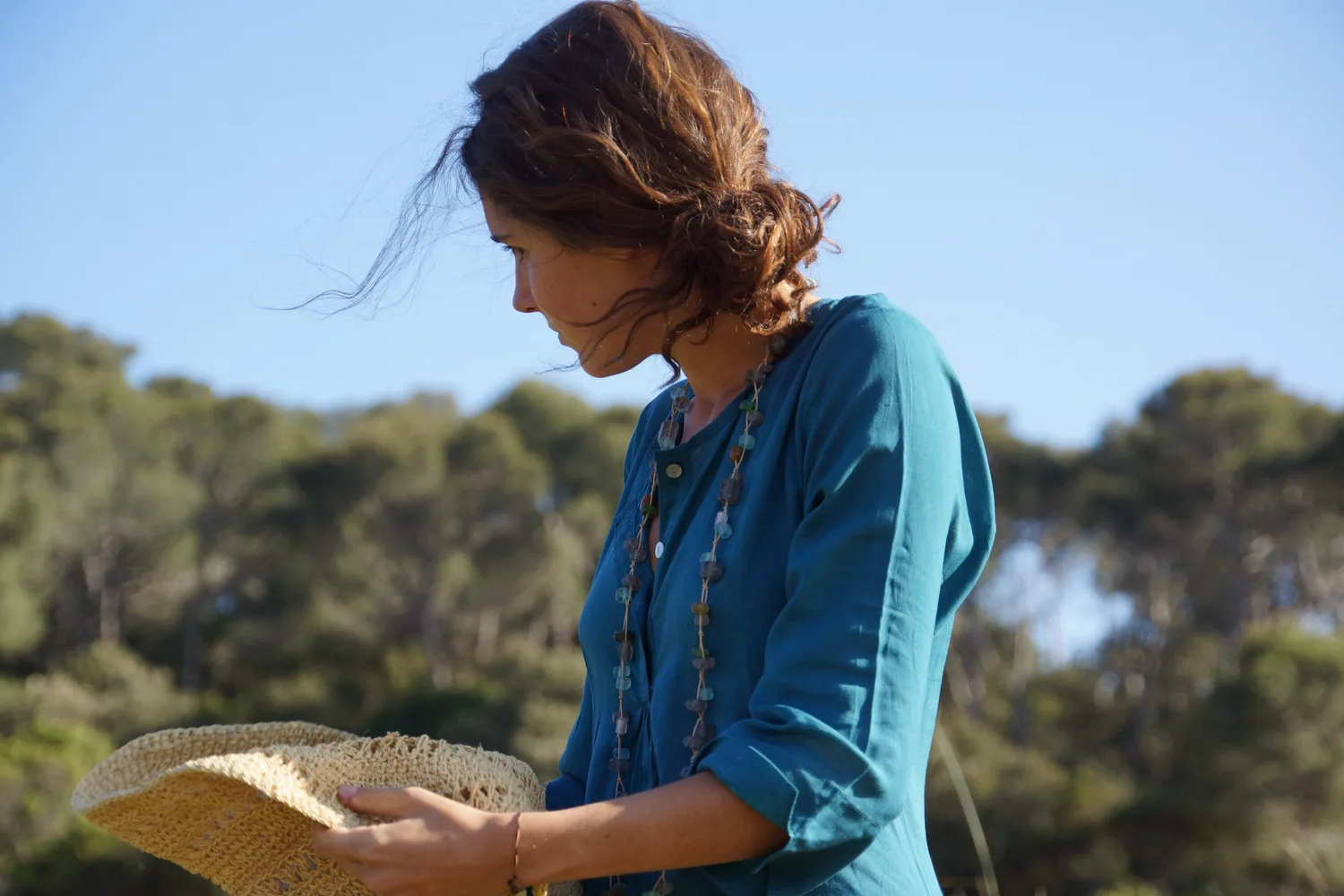Femme en tunique bleue et chapeau de paille dans le maquis de Porquerolles.