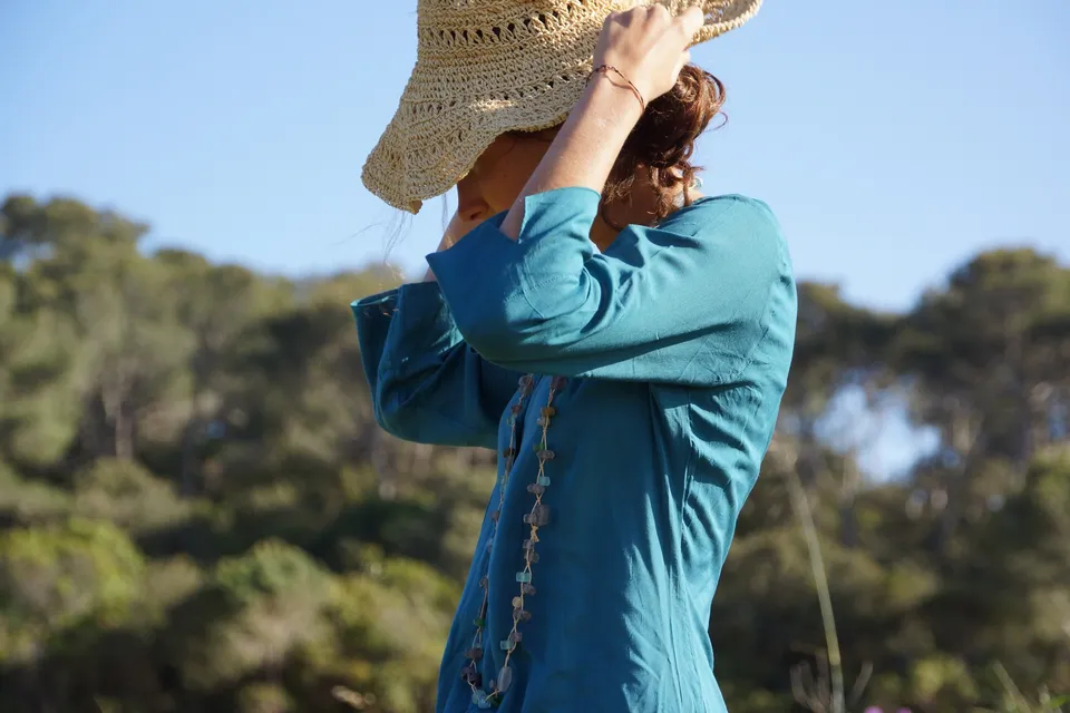 Femme en tunique bleue et chapeau de paille dans le maquis de Porquerolles.