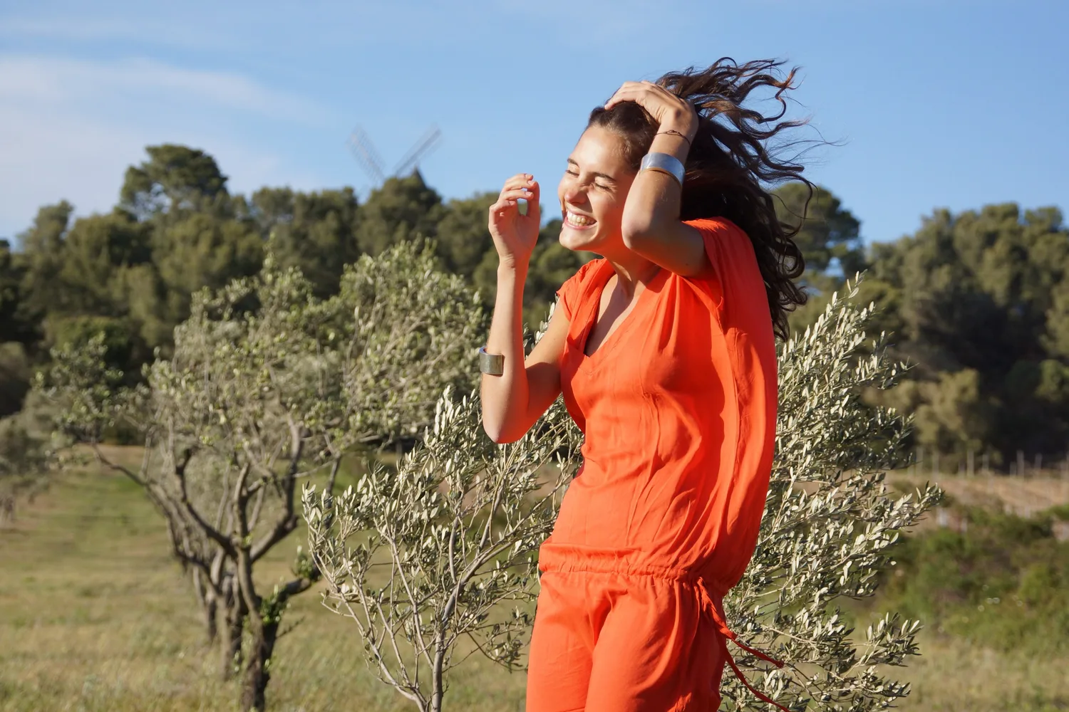 Femme en robe orange dans un paysage d’oliviers à Porquerolles.