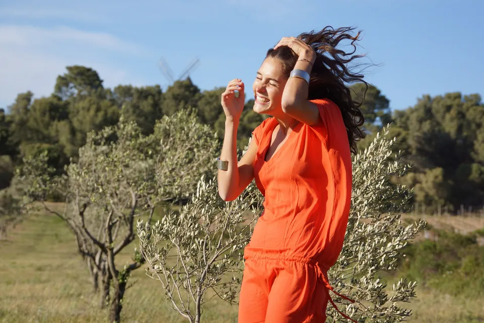 Femme en robe orange dans un paysage d’oliviers à Porquerolles.