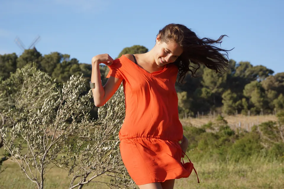 Femme en robe orange dans un paysage d’oliviers à Porquerolles.