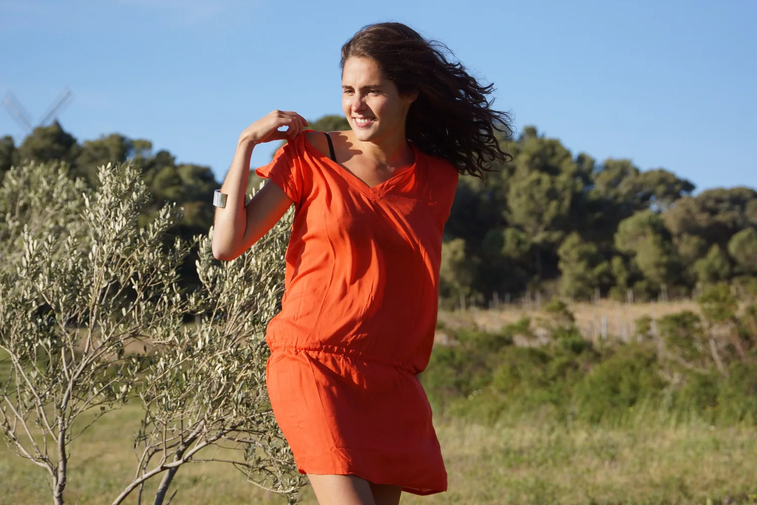 Femme en robe orange dans un paysage d’oliviers à Porquerolles.