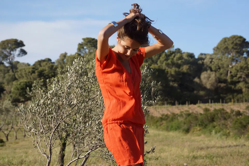 Femme en robe orange dans un paysage d’oliviers à Porquerolles.