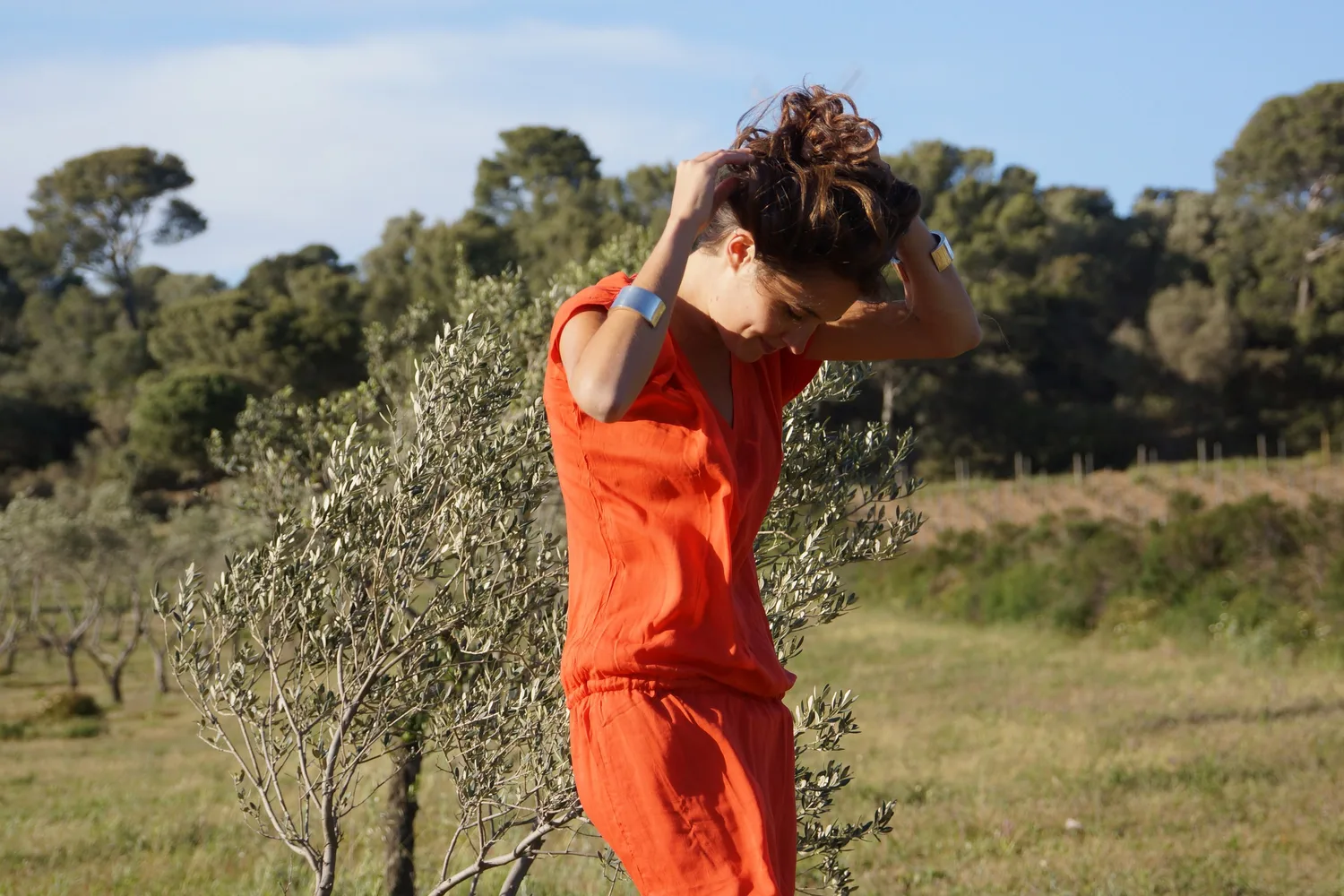Femme en robe orange dans un paysage d’oliviers à Porquerolles.