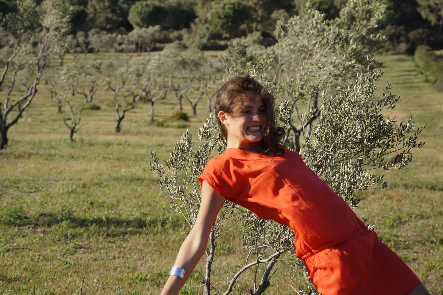 Femme en robe orange dans un paysage d’oliviers à Porquerolles.