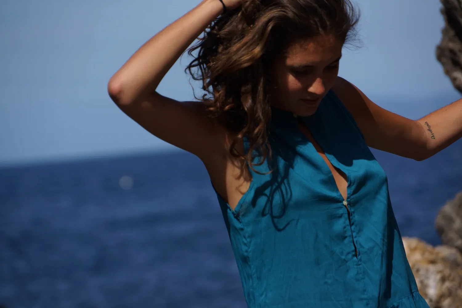 Femme en robe bleue au bord de la mer sur les rochers de Porquerolles.