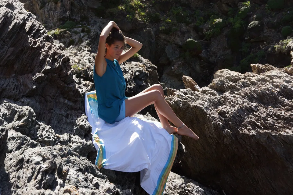 Femme en robe bleue au bord de la mer sur les rochers de Porquerolles.