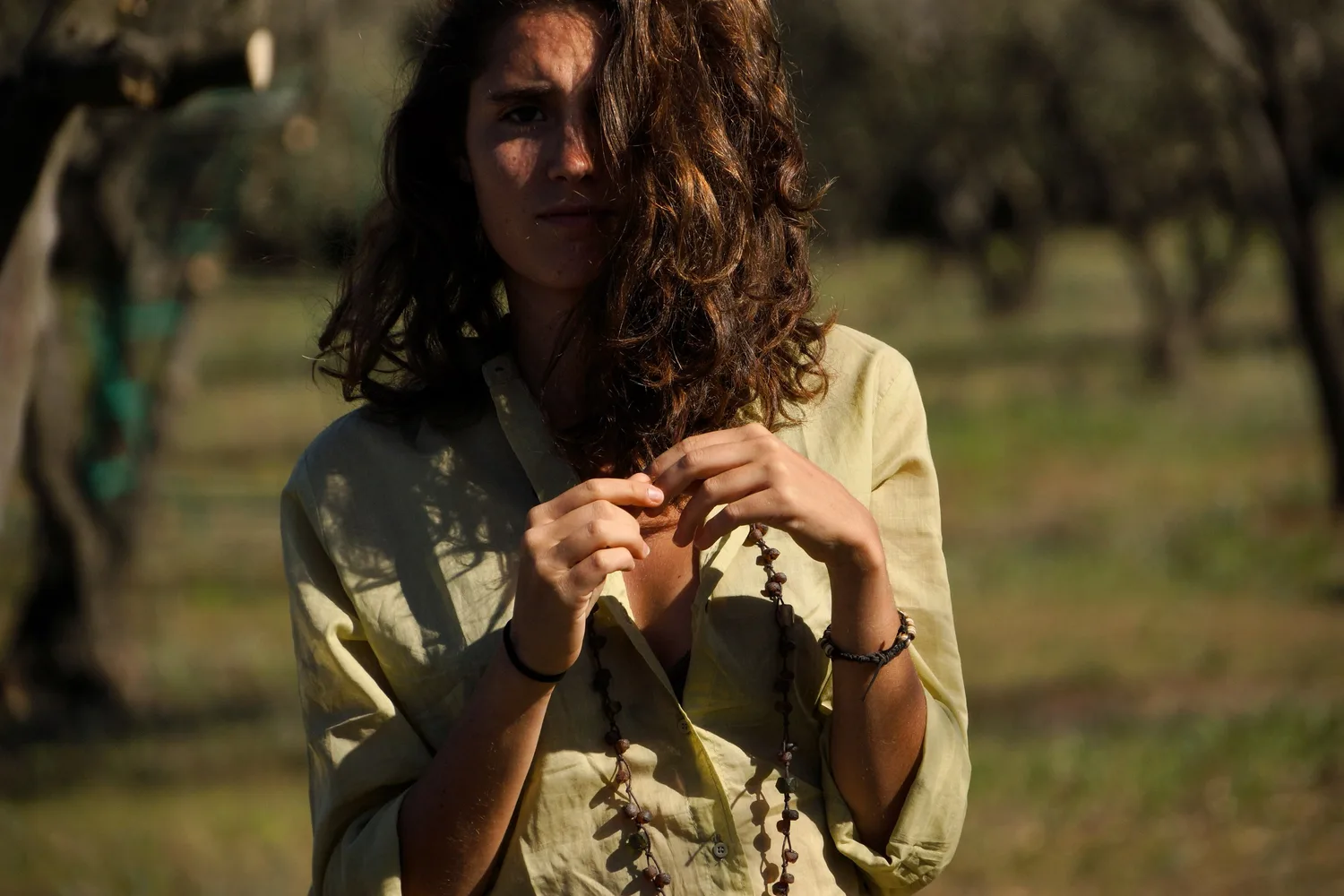Femme en blouse claire et pantalon blanc dans une oliveraie à Porquerolles.