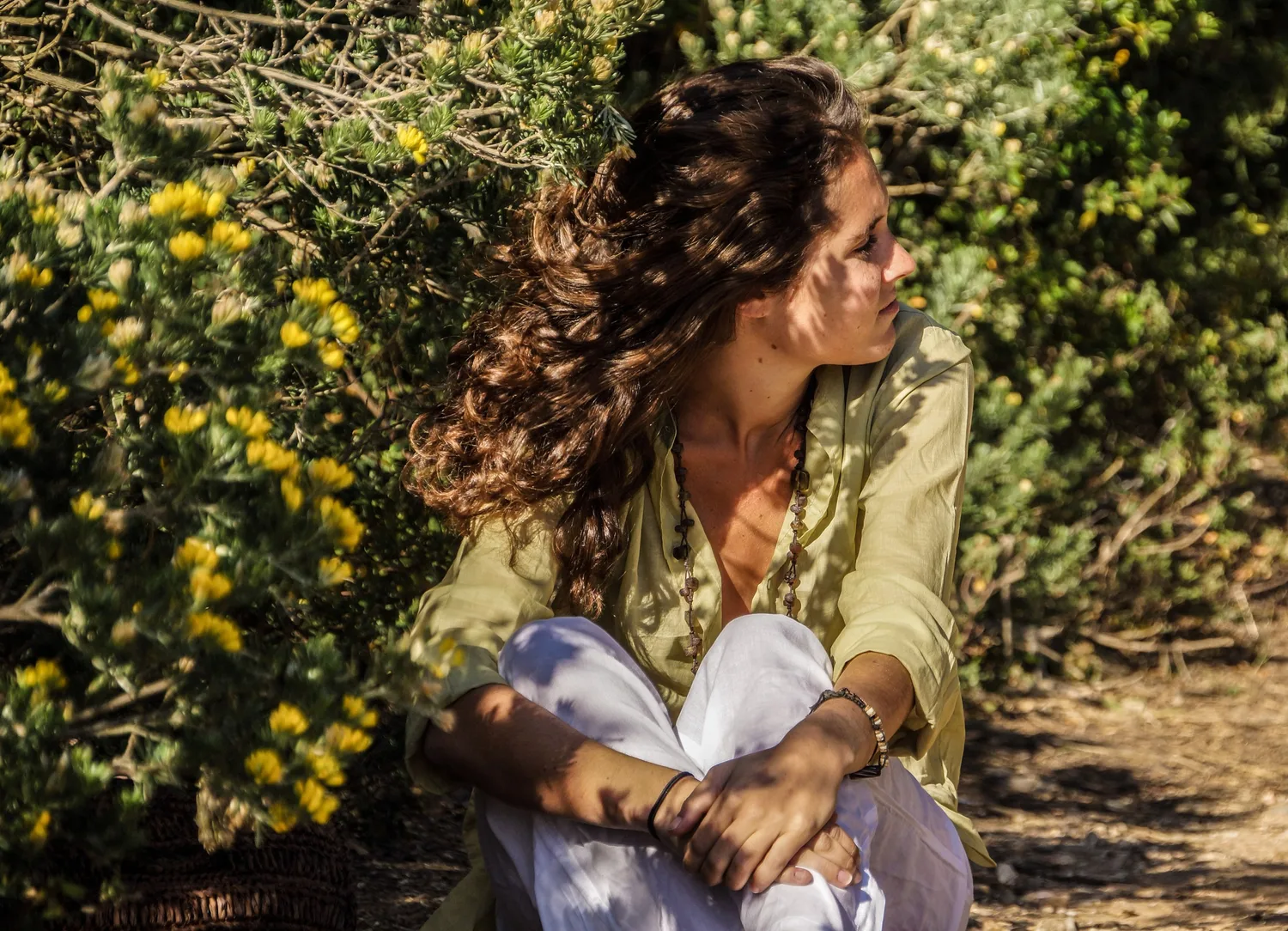 Femme en blouse claire et pantalon blanc dans une oliveraie à Porquerolles.