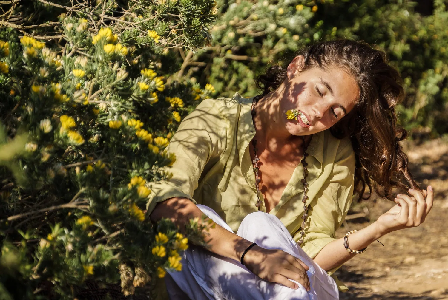 Femme en blouse claire et pantalon blanc dans une oliveraie à Porquerolles.
