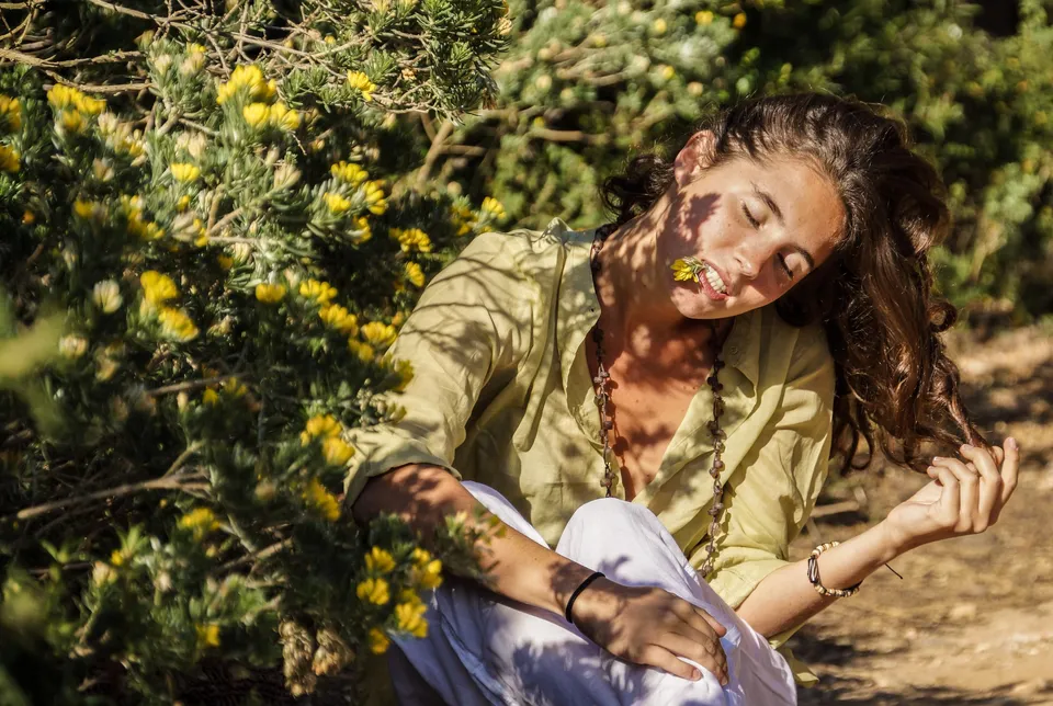 Femme en blouse claire et pantalon blanc dans une oliveraie à Porquerolles.