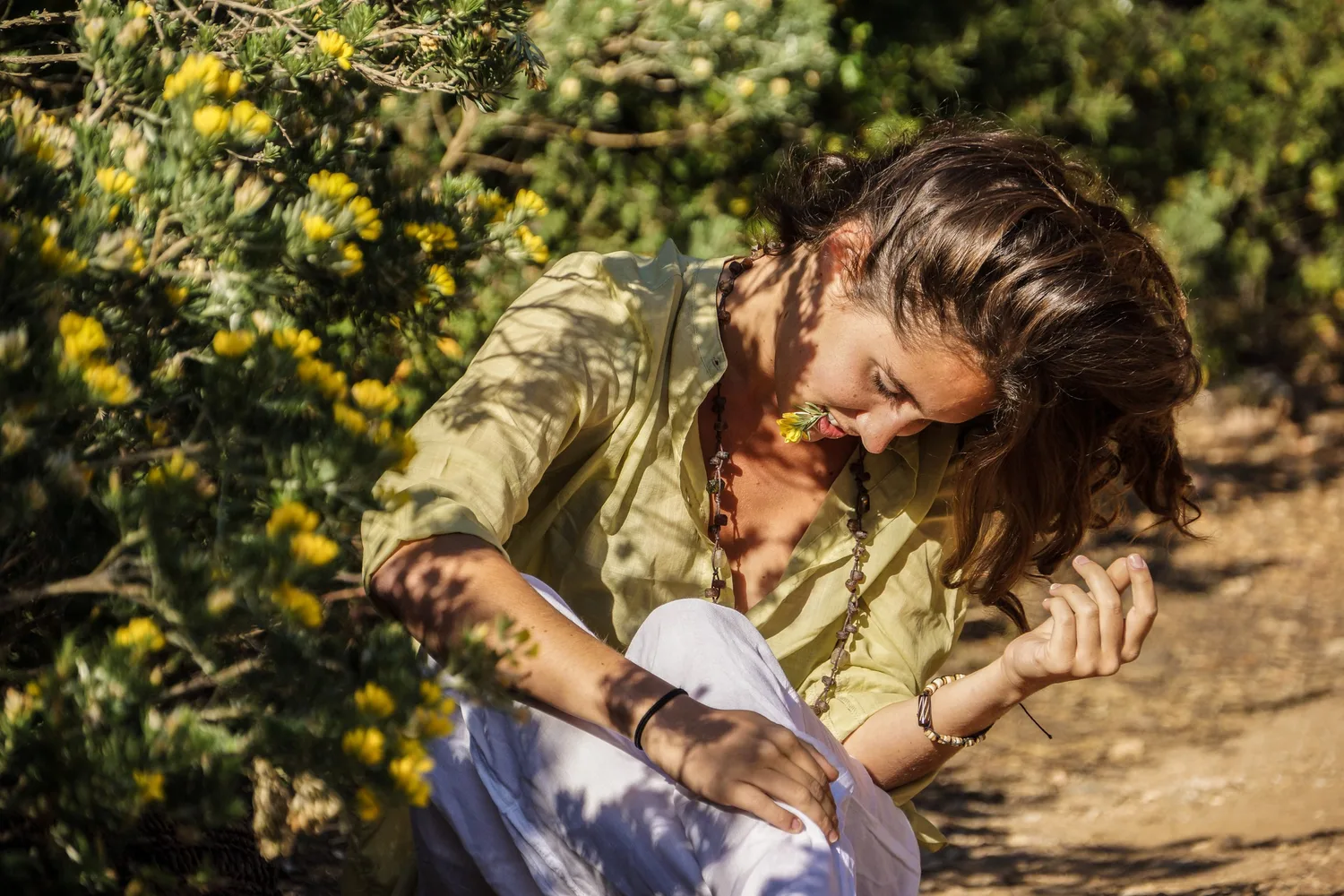 Femme en blouse claire et pantalon blanc dans une oliveraie à Porquerolles.