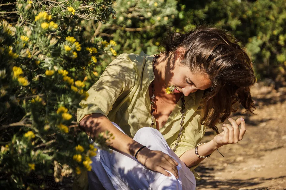 Femme en blouse claire et pantalon blanc dans une oliveraie à Porquerolles.