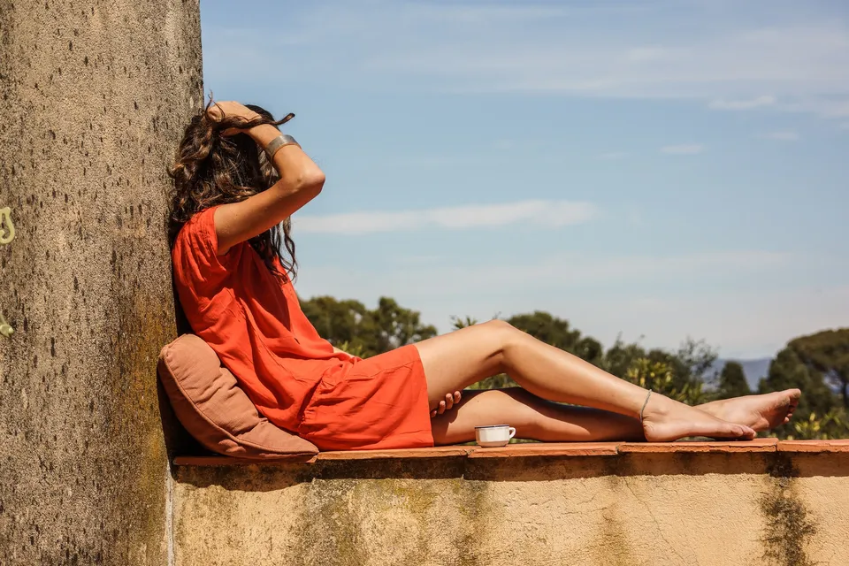 Femme en robe orange devant une architecture claire à Porquerolles.