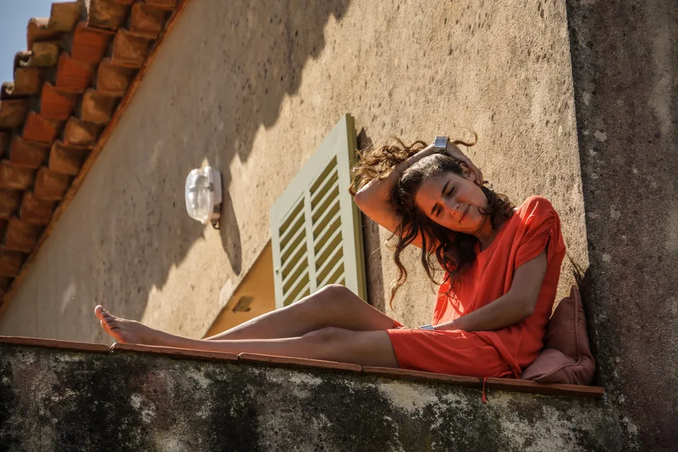 Femme en robe orange devant une architecture claire à Porquerolles.