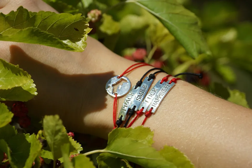 Gros plan de bracelets à plaques gravées sur cordons, parmi les feuilles d'un mûrier, à Porquerolles.
